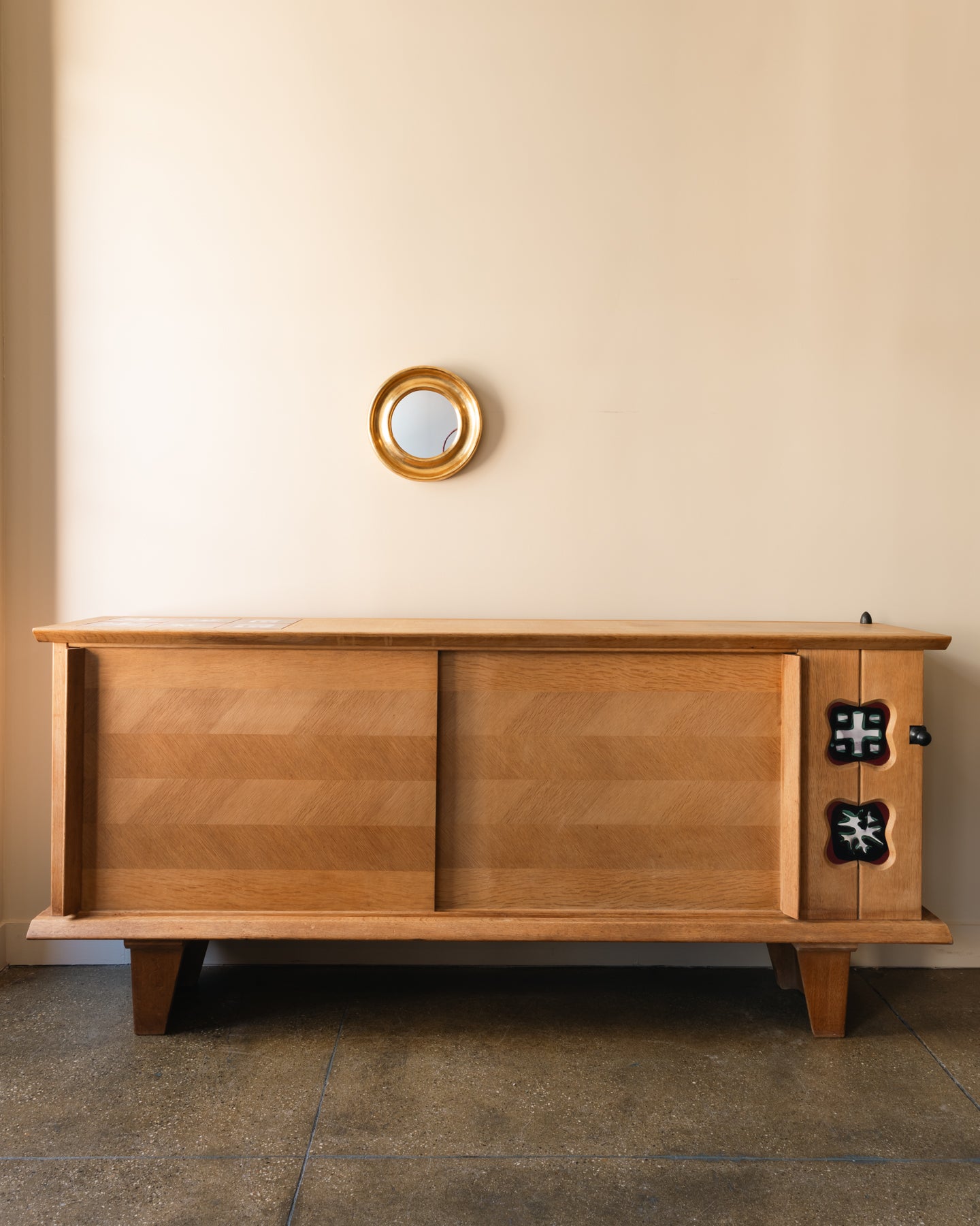 Oak buffet by Guillerme & Chambron showing right-side Danikowski ceramic panel and left-side sliding oak doors; France, 1960s.