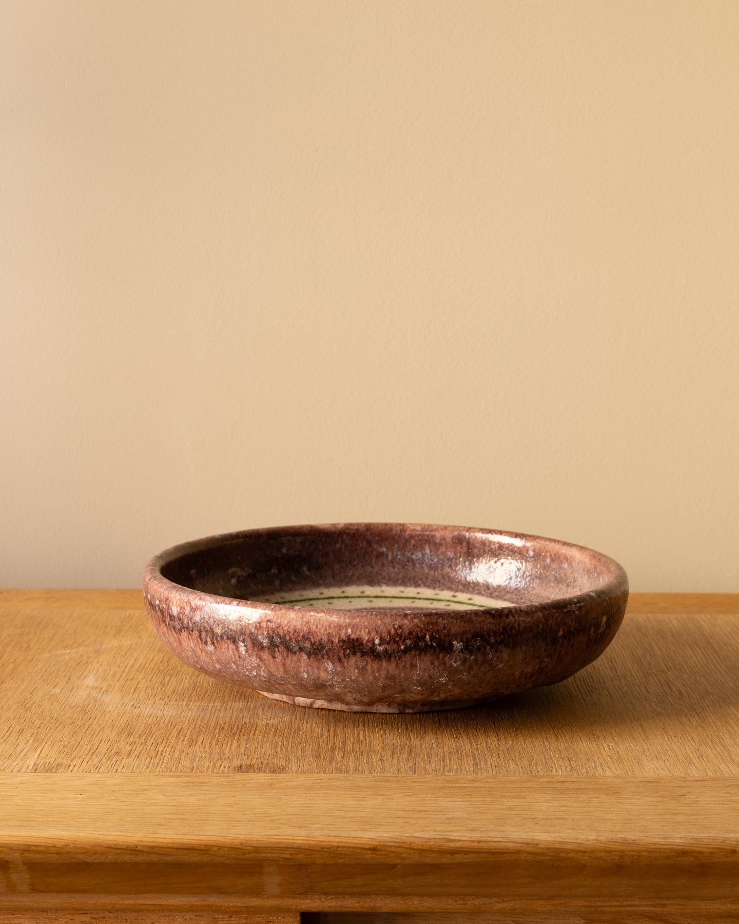 Image of Guido Gambone ceramic bowl showing figural decoration in green on a cream field with purple glaze, Italy 1950s.