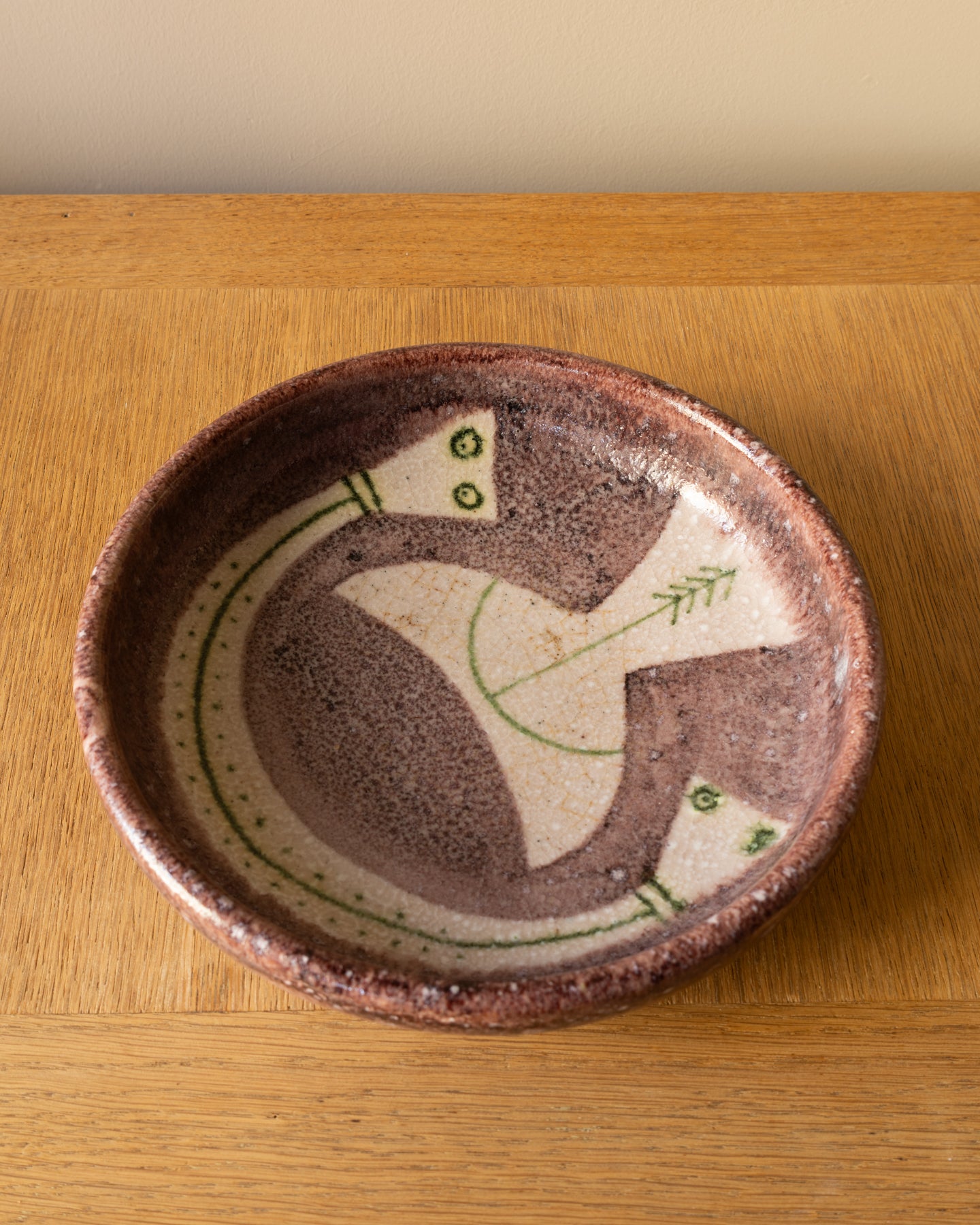 Image of Guido Gambone ceramic bowl showing figural decoration in green on a cream field with purple glaze, Italy 1950s.