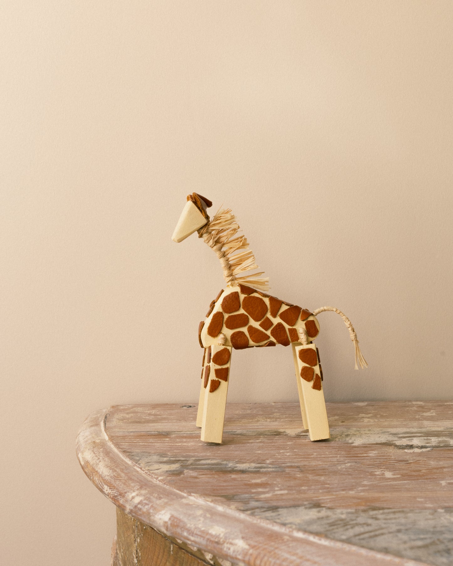 Handmade giraffe figure by Alicia Sciberras with timber body, leather details, and raffia accents.